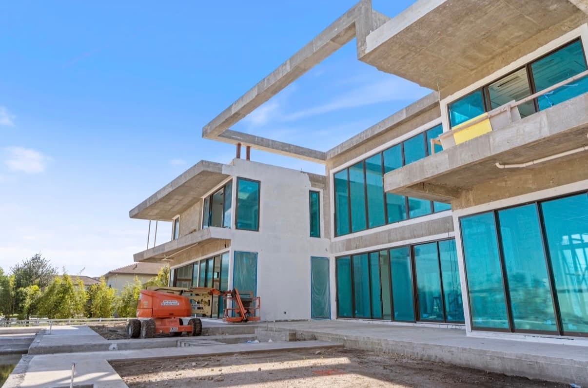 Modern mansion construction showing structural framing and glass installation